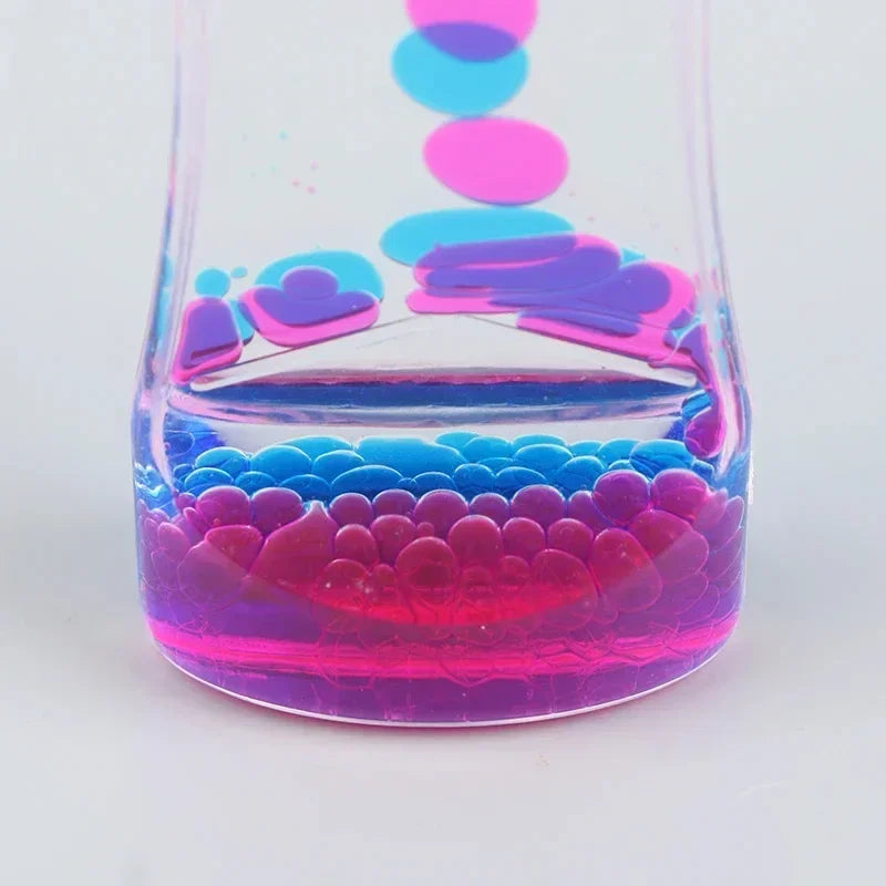A glass hourglass filled with colorful liquid showing layered colors and bubbles.