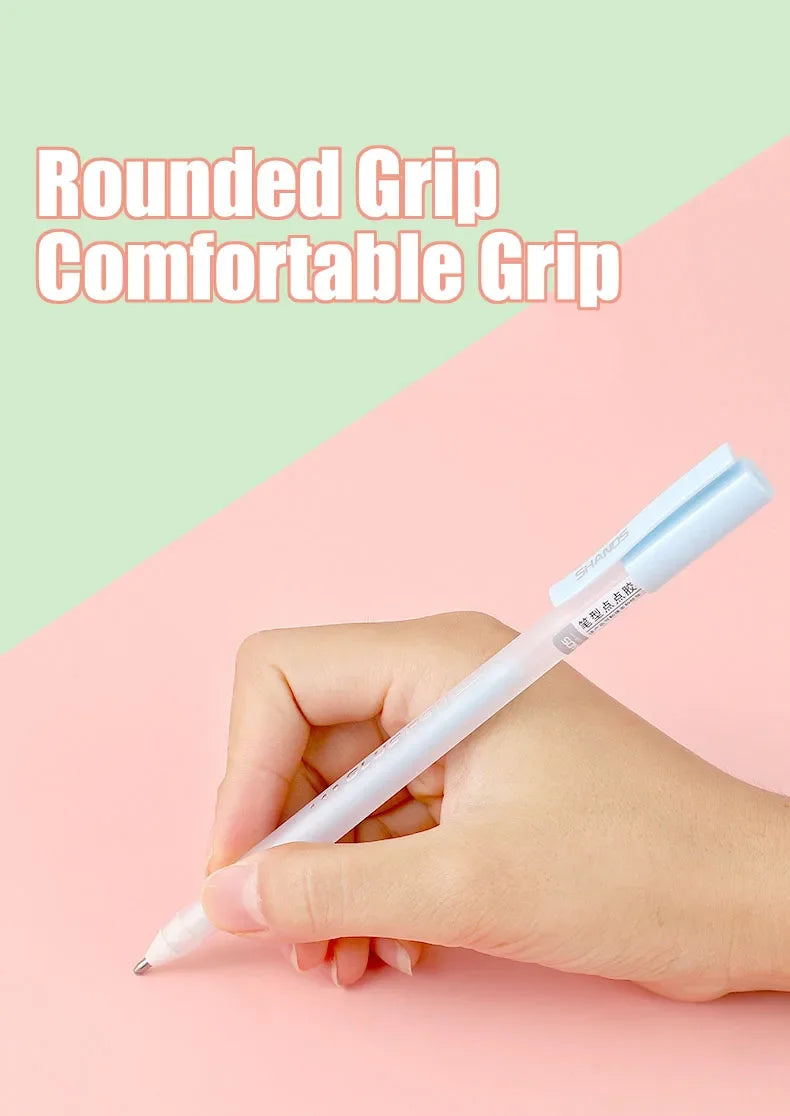 A hand holds a white glue pen with a rounded grip against a pink and green background.