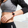 A close-up of a woman wearing a dark gray cropped top and a brown leather watch with quick release pins on her wrist.