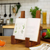 A vintage wooden cookbook holder stands on a table, displaying an open recipe book with handwritten lines.
