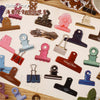 A collection of vintage metal clip themed stickers for journaling and scrapbooking displayed on a grid.