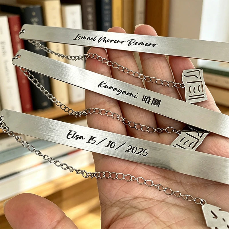 Hand holding several stainless steel bookmarks engraved with names and dates