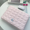 A pink quilted laptop sleeve with a heart pattern is shown next to a white computer mouse and a Kinfolk magazine.