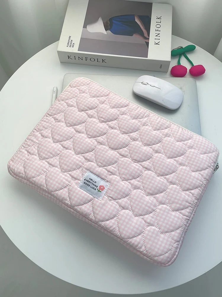 A pink quilted laptop sleeve with a heart pattern is shown next to a white computer mouse and a Kinfolk magazine.