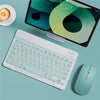 A white portable Bluetooth keyboard is shown next to an iPad displaying a green and black interface and a teal wireless mouse