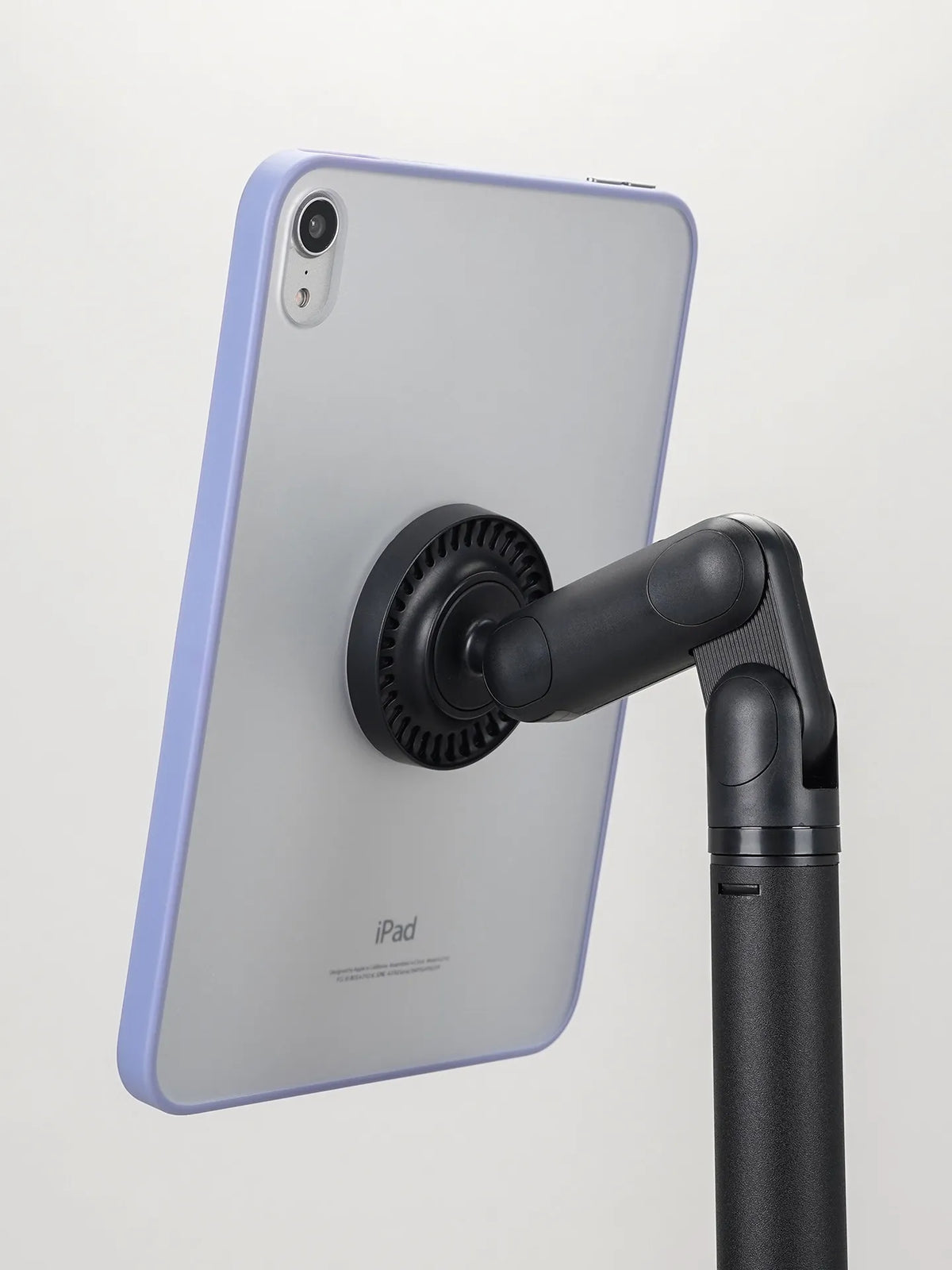 A light purple iPad is mounted on a black magnetic stand for viewing.