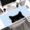 A black cat silhouette is printed on a light blue mouse pad placed on a white desk.