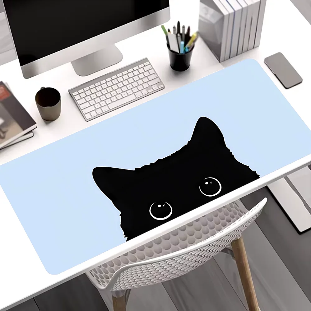 A black cat silhouette is printed on a light blue mouse pad placed on a white desk.