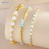 Gold-plated shell pearl beaded bracelets stacked on a light wooden surface