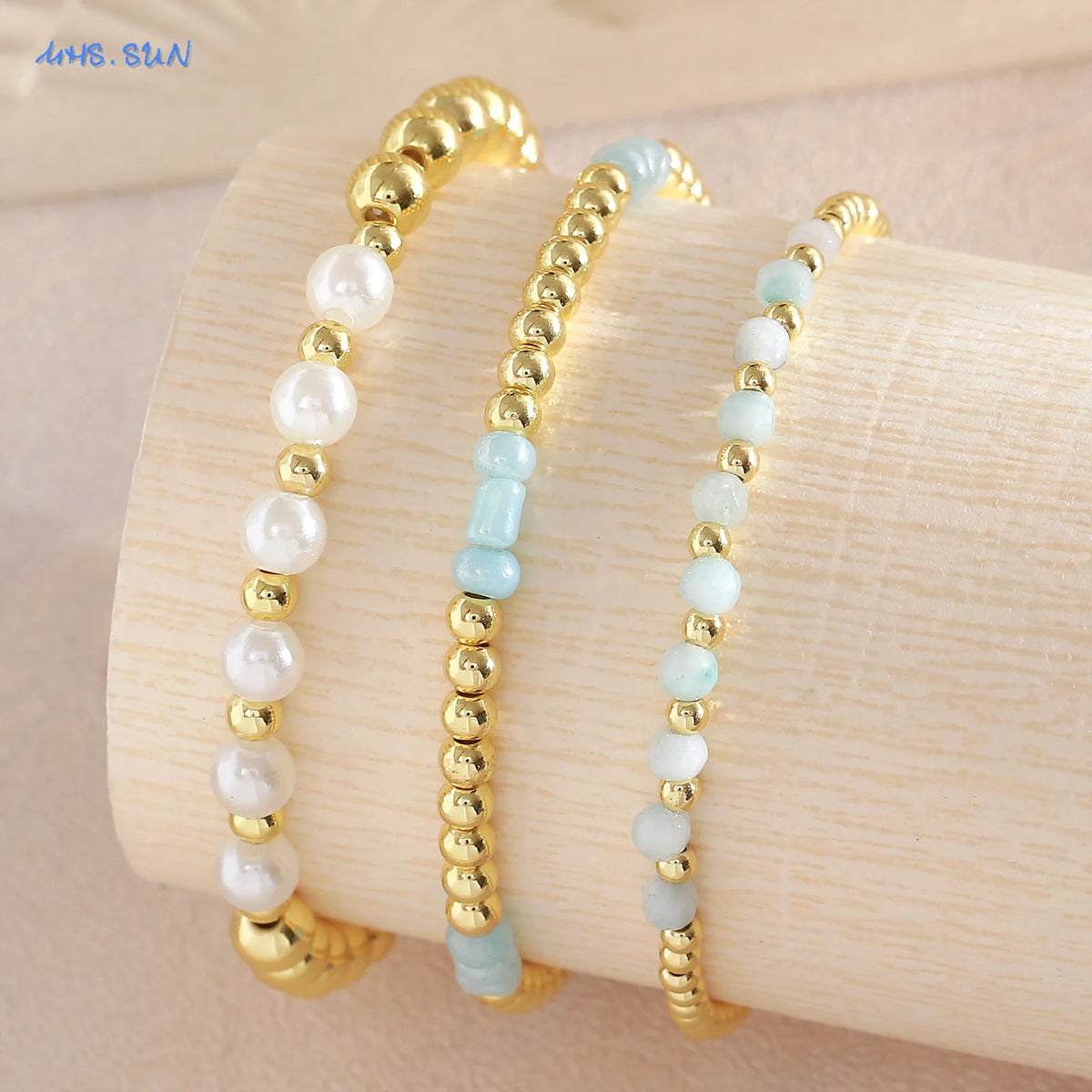 Gold-plated shell pearl beaded bracelets stacked on a light wooden surface