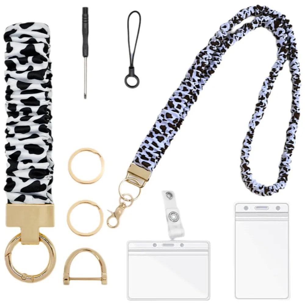 A black and white cow print stretchy lanyard with a gold clip and retractable reel for an ID badge.