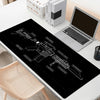 A black gaming mouse pad featuring a detailed outline of a rifle and various tactical elements on a white desk.