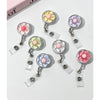A set of floral pull buckle retractable ID badge holders in pastel colors pink, yellow, and purple.