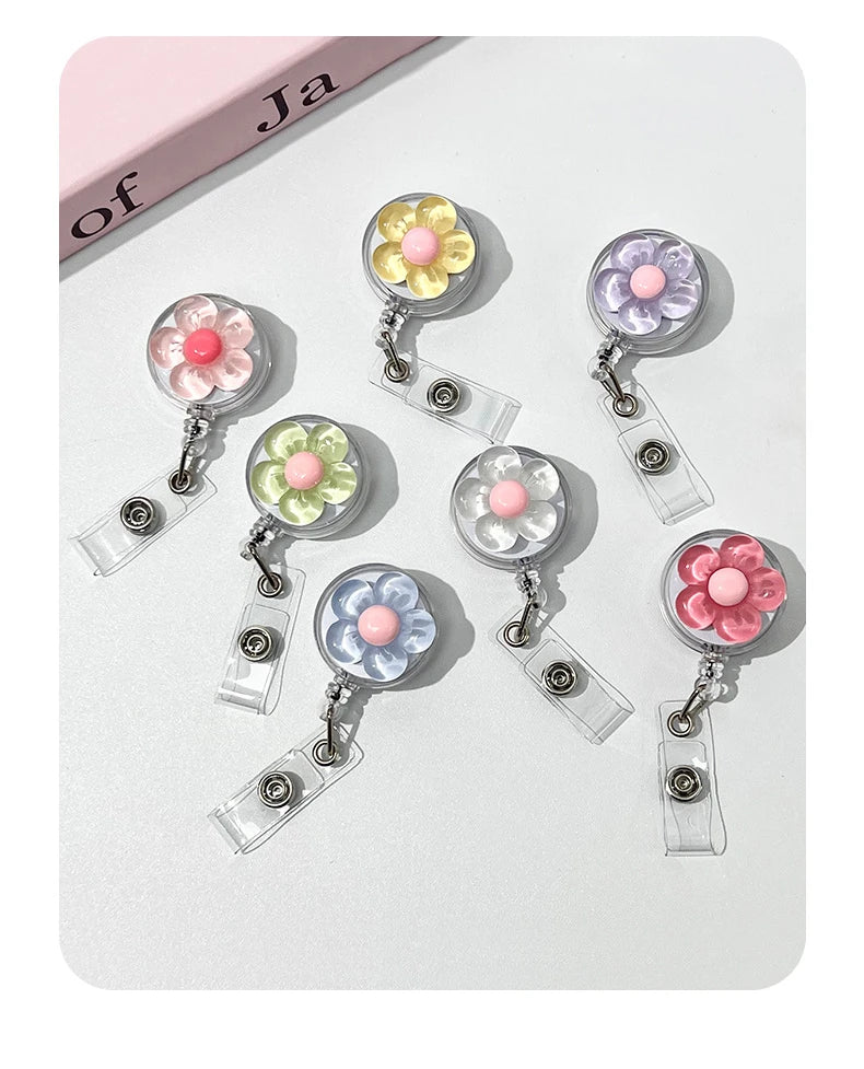 A set of floral pull buckle retractable ID badge holders in pastel colors pink, yellow, and purple.