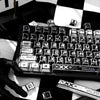 A close-up view of a black and white comic-style PBT keycap set on a keyboard, with various keycaps and accessories scattered