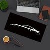 A black mouse pad featuring a white silhouette of a JDM car design, next to a laptop and writing tools.