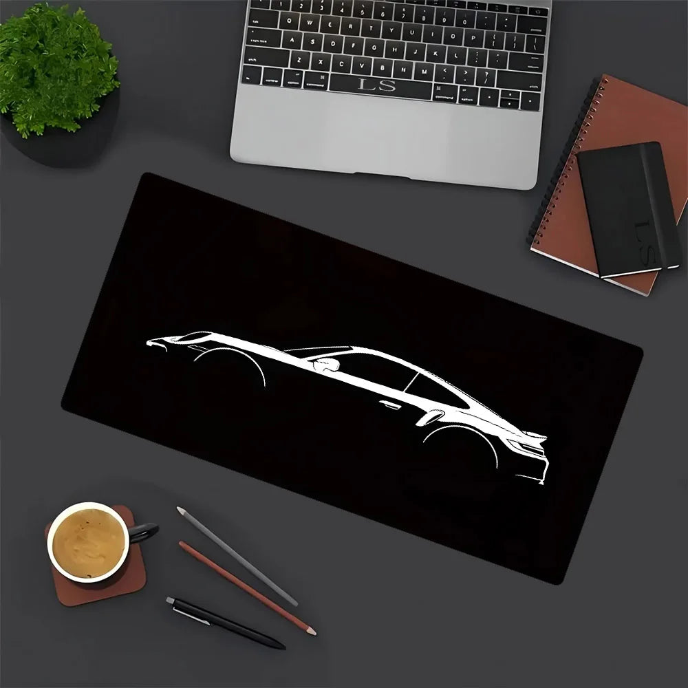 A black mouse pad featuring a white silhouette of a JDM car design, next to a laptop and writing tools.