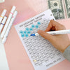 A hand writes on an envelope savings tracker sheet showing various dollar amounts and a total of $5,050.