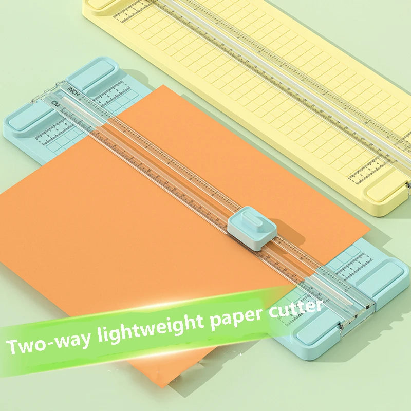 A two-way lightweight paper cutter with interchangeable blades shown alongside a yellow ruler and orange paper.