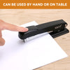 A hand is shown operating a black heavy-duty metal stapler on a white piece of paper.