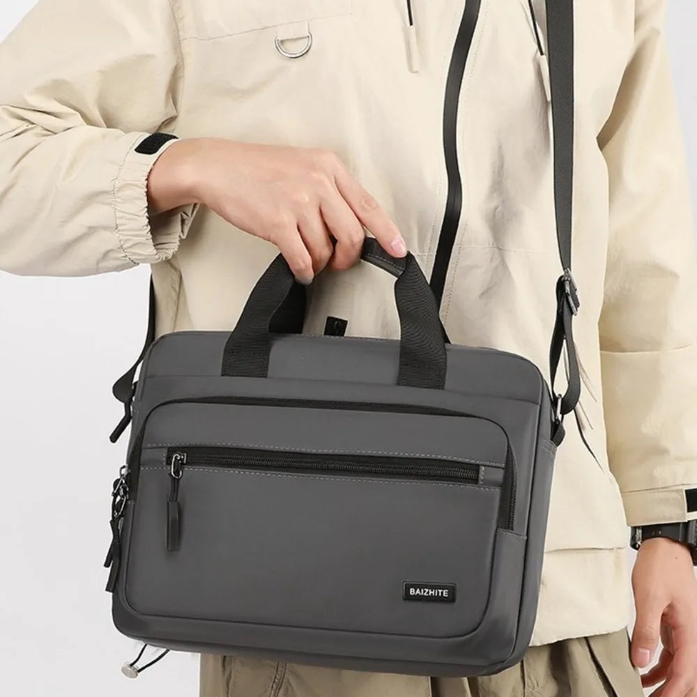 A gray Oxford cloth crossbody briefcase with a laptop compartment is shown being held by a person.