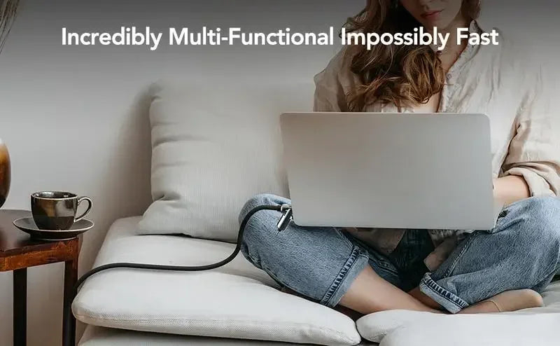 Eine Person lädt und synchronisiert einen Laptop mit einem Multifunktions-USB-C-Kabel, während sie auf einer Couch entspannt.