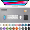 A large PU leather desk mat is shown with a laptop, keyboard, mouse, and a cup on a gray desk surface.