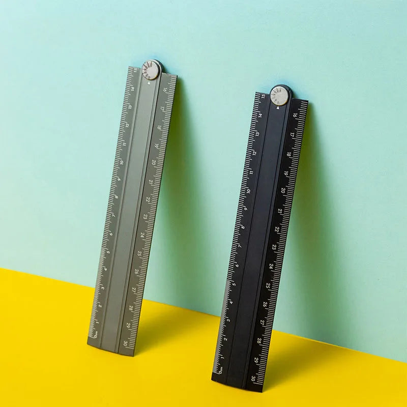 A black aluminum folding ruler with millimeter markings is shown against a light blue background.