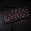 A close-up view of a black mechanical keyboard with red backlit carbon fiber keycaps resting on a dark surface.