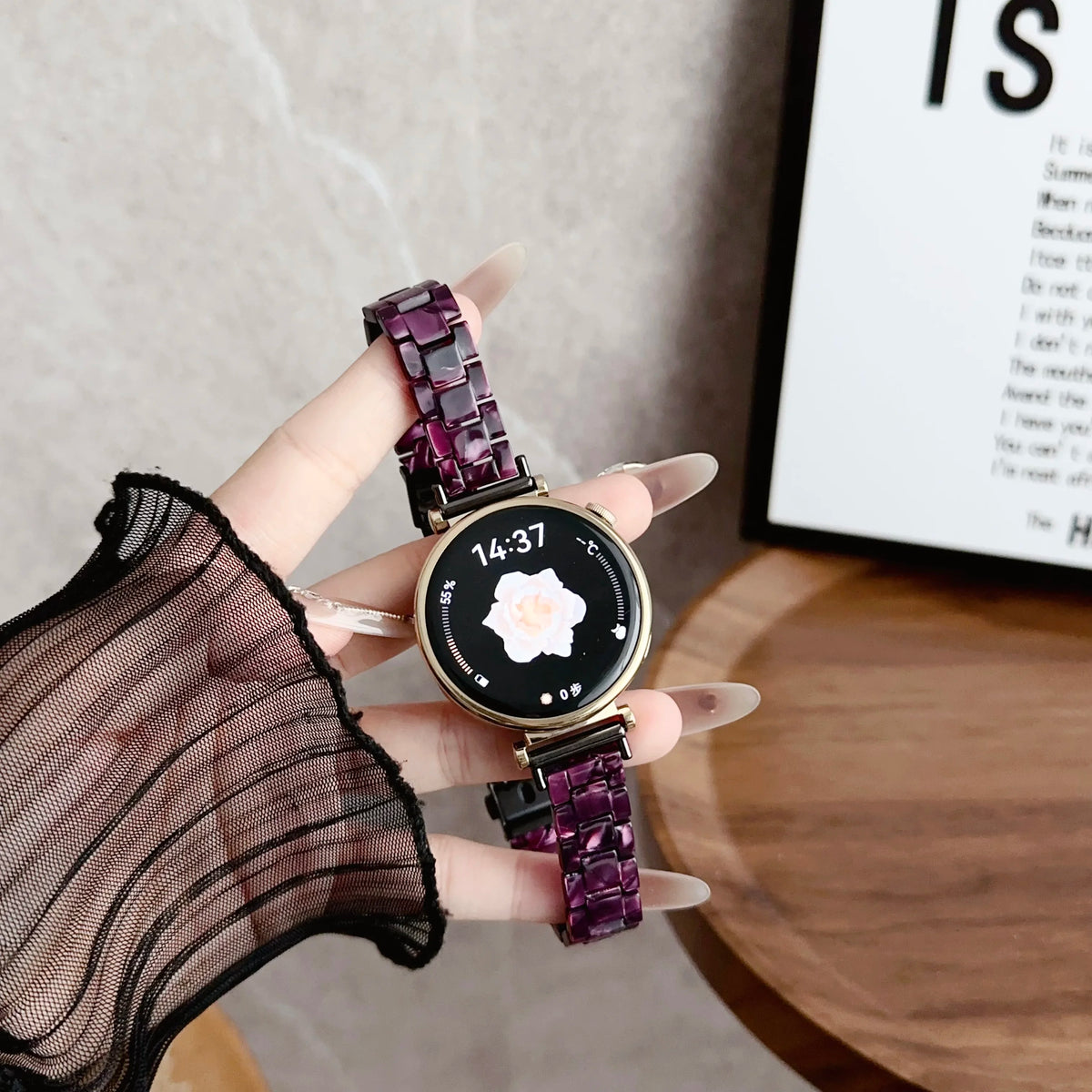 A hand holds a purple resin beaded watch with a black face and a dark purple strap, displaying the time 14:37.