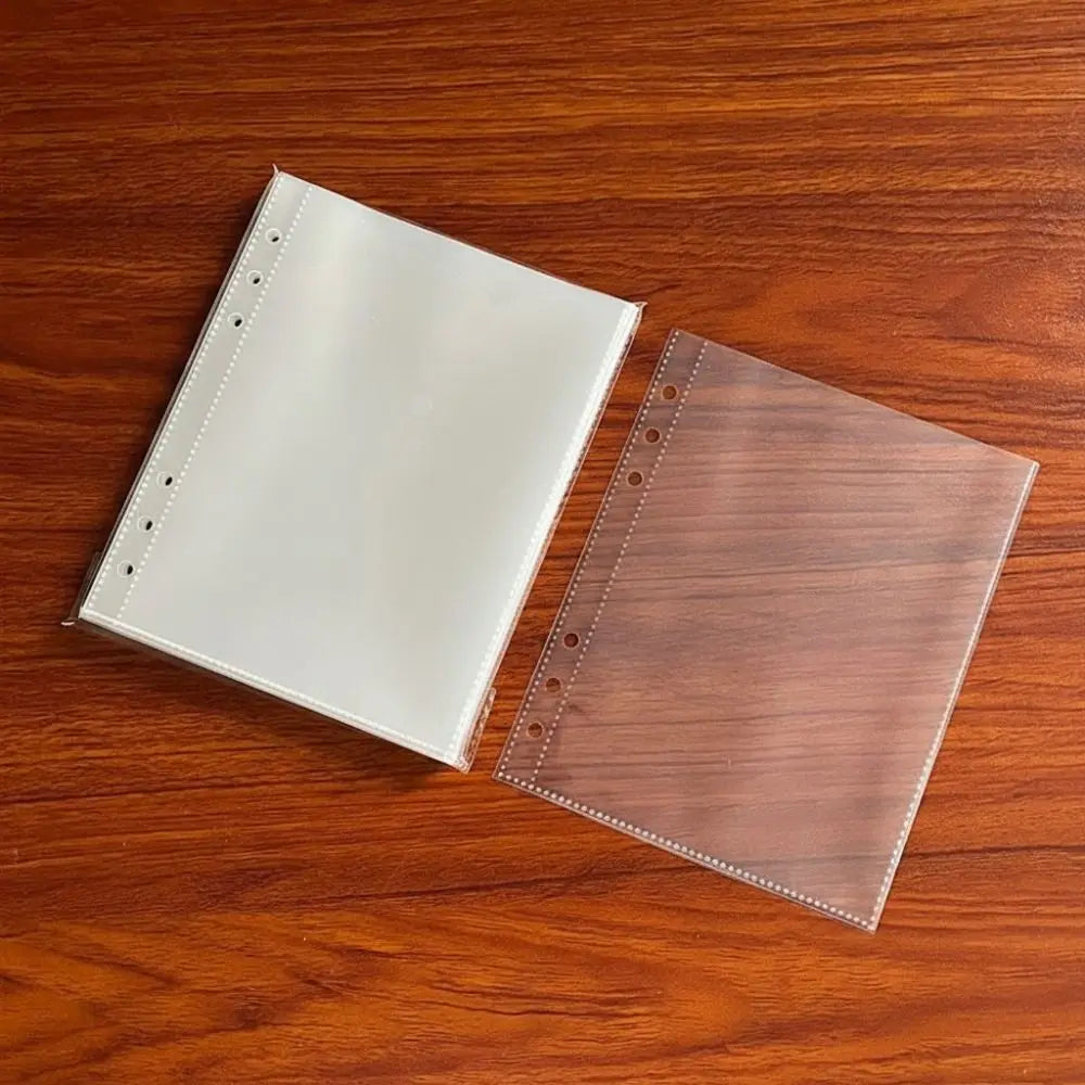 A pair of A5 transparent photo card binder sleeves, one white and one brown, resting on a wooden surface.