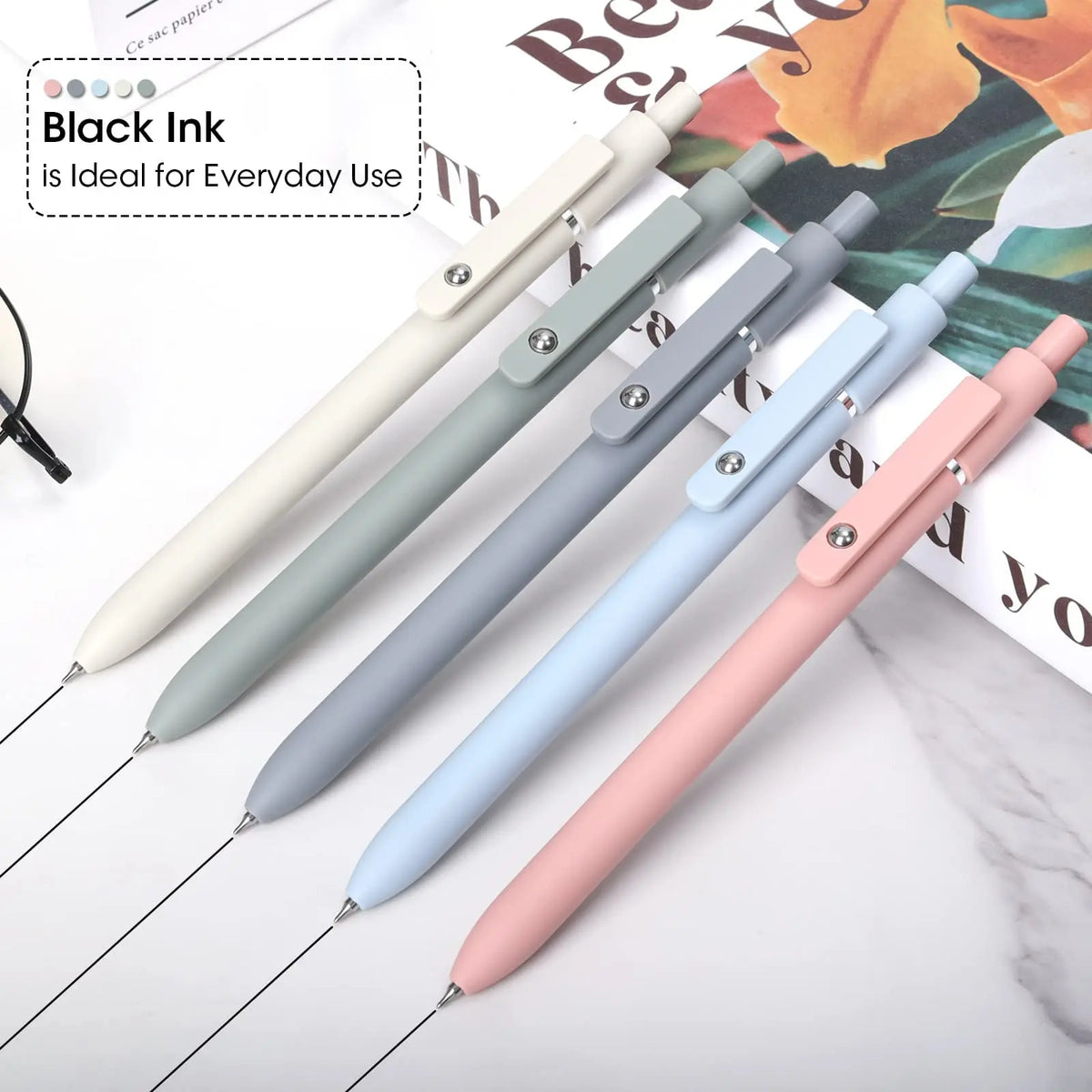 A collection of fine point gel pens in various colors, including black, gray, blue, and pink, shown on a white background.