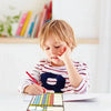 A young child is using a magnetic weekly chore chart for kids on a table.