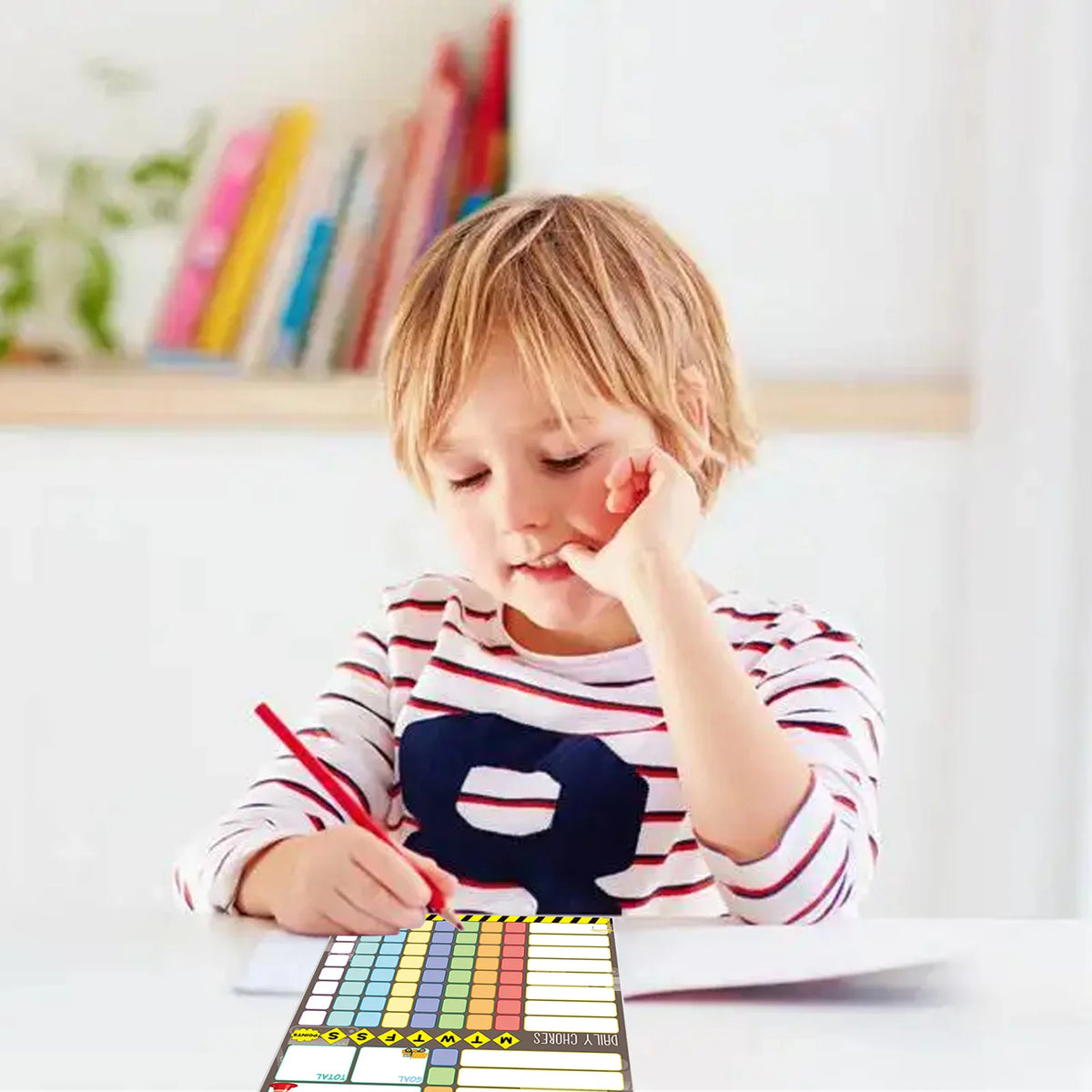 A young child is using a magnetic weekly chore chart for kids on a table.