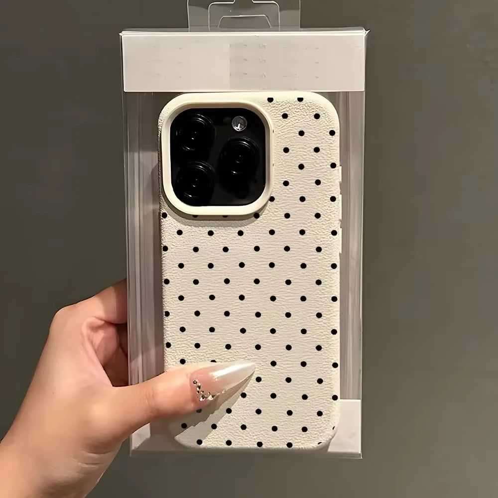 A hand holds a white polka dot textured phone case with a soft-touch grip inside its clear packaging.