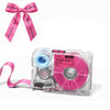A pink ribbon bow is shown next to a clear label maker device with a pink roller and black ink.
