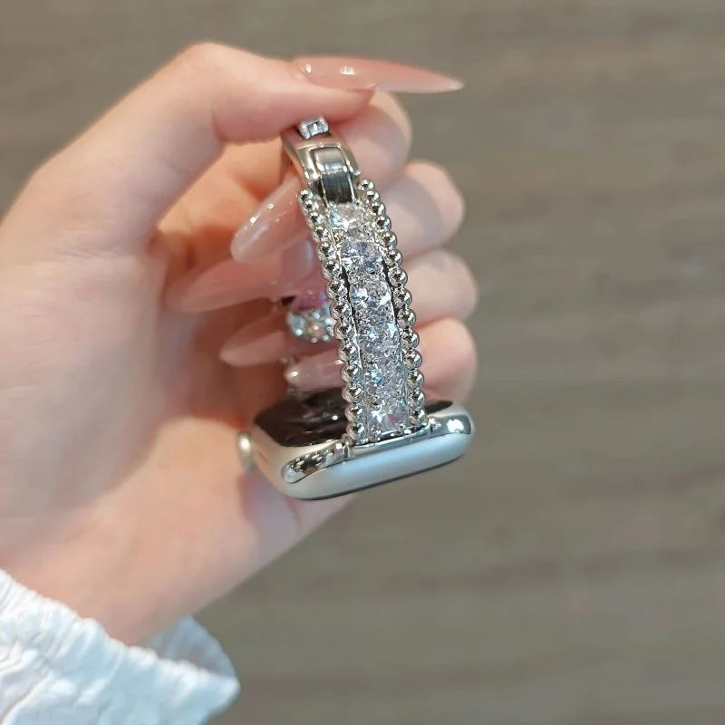 A hand holds a crystal-embellished watch strap featuring sparkling zircon accents.