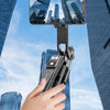 A hand holds a portable Bluetooth selfie stick tripod with a fill light and remote, capturing a cityscape.