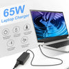 A black 65W laptop charger AC adapter plugged into a white laptop.