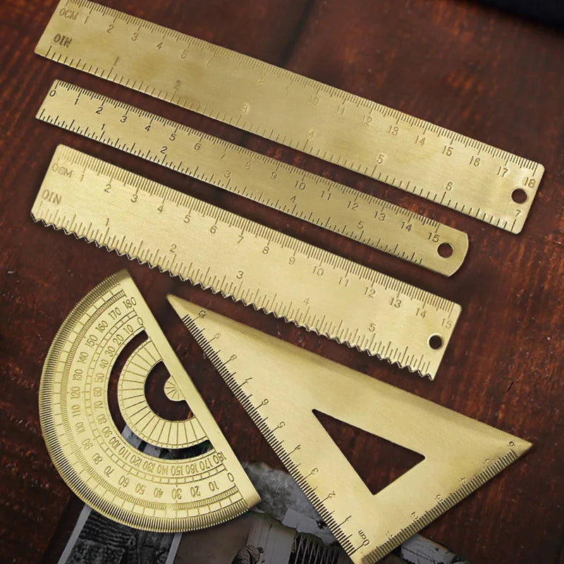 A set of brass drafting tools including rulers and triangles laid on a wooden surface.