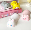 A collection of pink and yellow kawaii ergonomic wrist rests shaped like cats and pigs are displayed on a white surface.