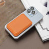 A light gray magnetic leather wallet with an orange stand case resting on a brown surface.