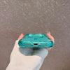A hand holds a teal colored shockproof magnetic case with a glitter finish for an iPhone.