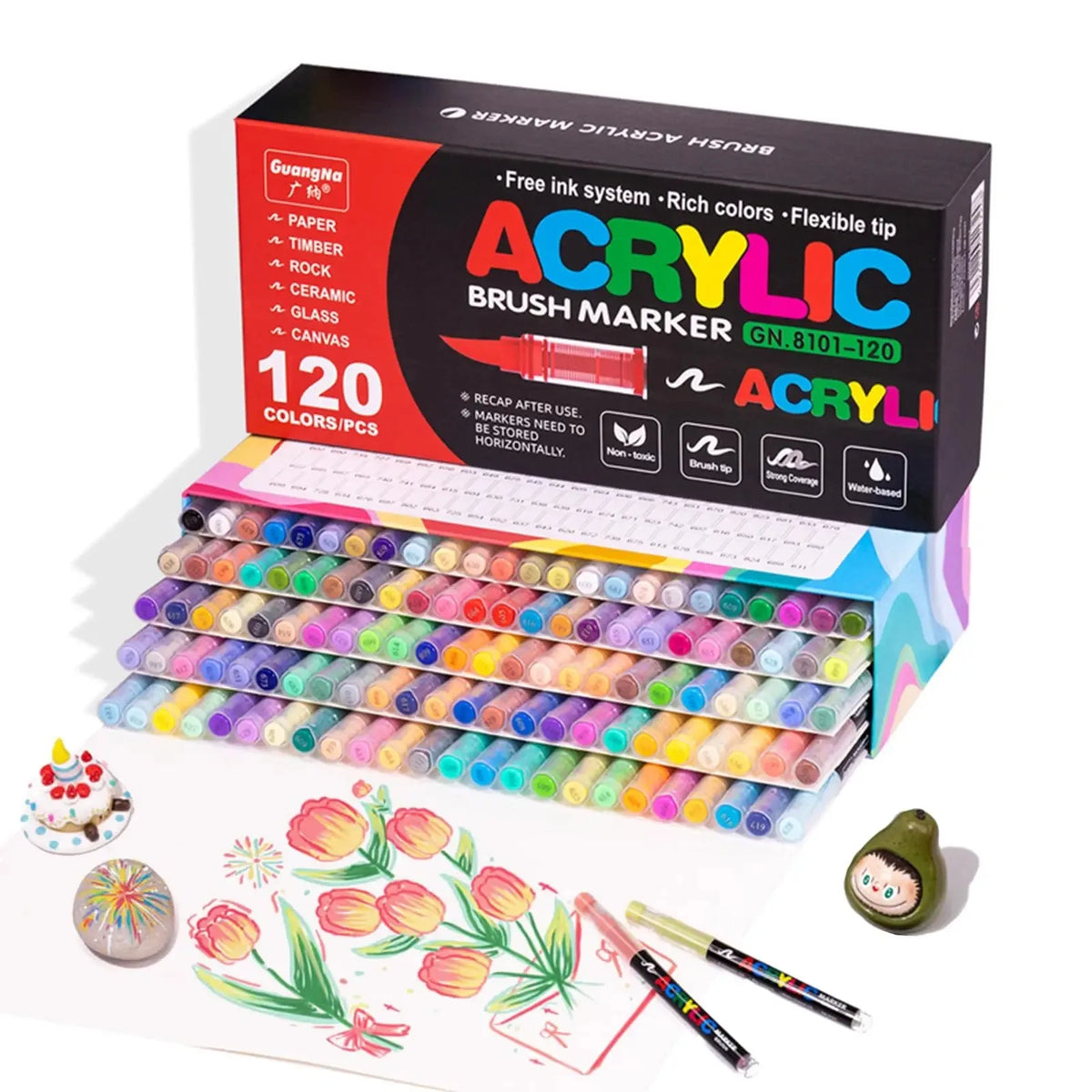 A box of acrylic brush markers with various colors and tips, alongside some individual markers and a sheet of artwork.