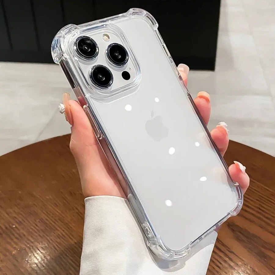 A clear shockproof phone case for an iPhone is held in a person's hand against a wooden surface.