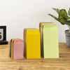 Une collection d'enveloppes en papier colorées dans différentes nuances de rose, jaune et vert sont présentées sur une surfac