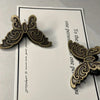 A vintage butterfly metal book clip with an ornate design is shown against a white card.