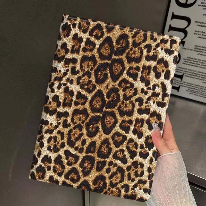 A close-up of a leopard print protective skin for an iPad case being held by a hand.