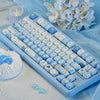 A close-up of blue sea themed PBT keycaps for a mechanical keyboard displayed on a light blue cloth.