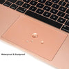 A close-up view of a rose gold trackpad protector for a MacBook, highlighting waterproof and dustproof features.